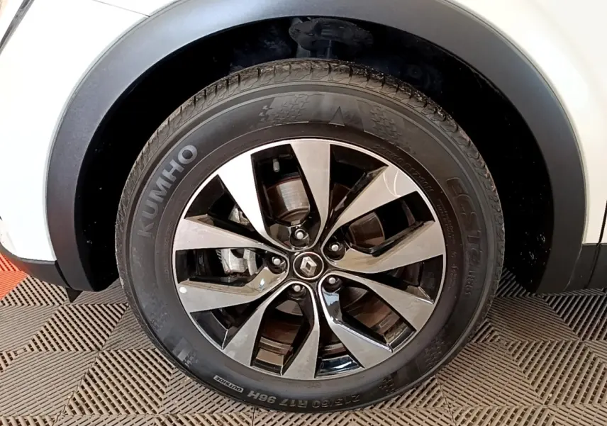 Gros plan sur la roue avant droite du Renault Arkana blanc, avec jante alliage bicolore et logo Renault central.