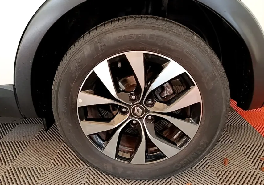 Gros plan sur la roue avant droite d’un Renault Arkana blanc, jante alliage bicolore au design moderne.