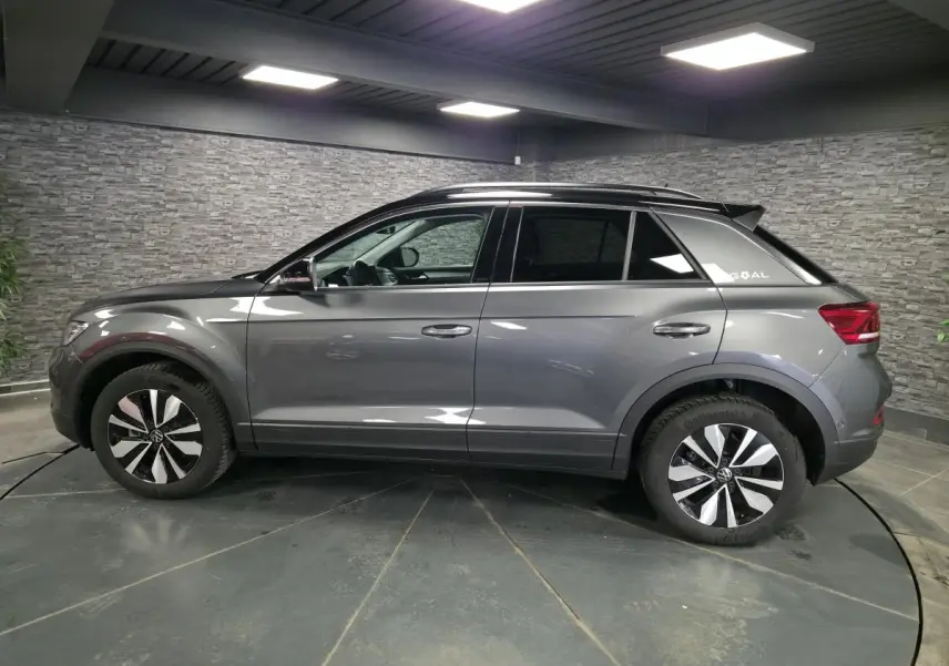 Volkswagen T-Roc gris en profil droit, avec jantes alliage 17 pouces et sticker édition GOAL sur custode arrière.