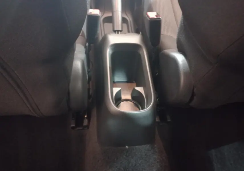 Vue rapprochée de la console centrale arrière noire entre les sièges avant d'une Citroën C3 2024.