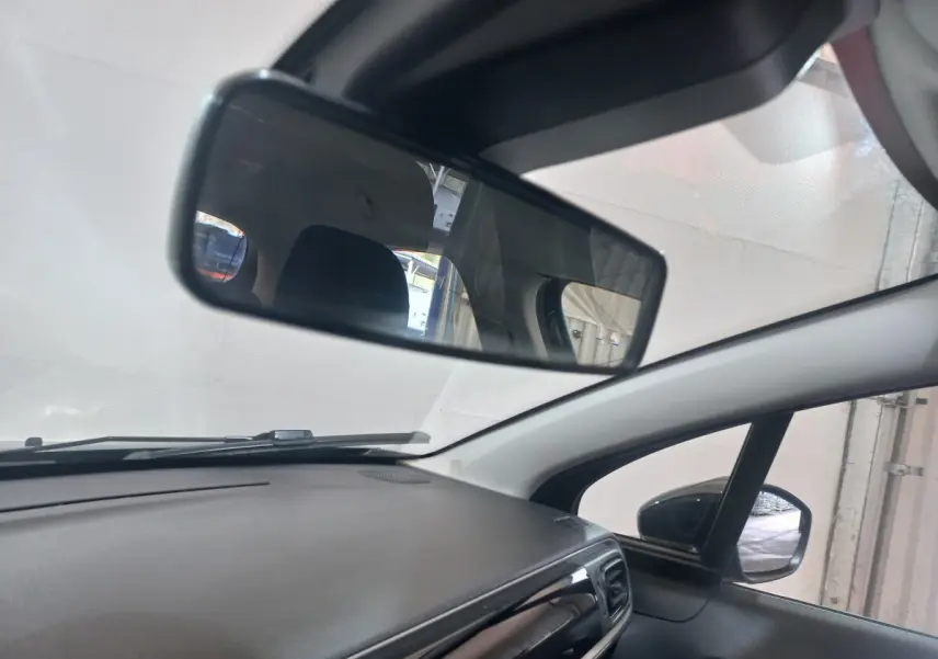 Vue intérieure du tableau de bord et rétroviseur d'une Citroën C3 noire, version 2024, côté droit visible.
