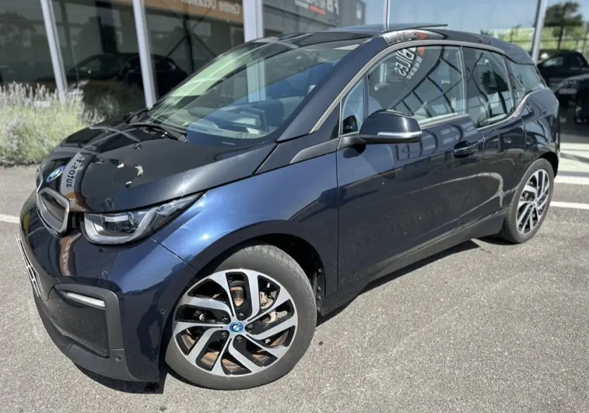 BMW i3 électrique bleue vue en 3/4 avant droit, mettant en valeur ses jantes distinctives et son design compact.