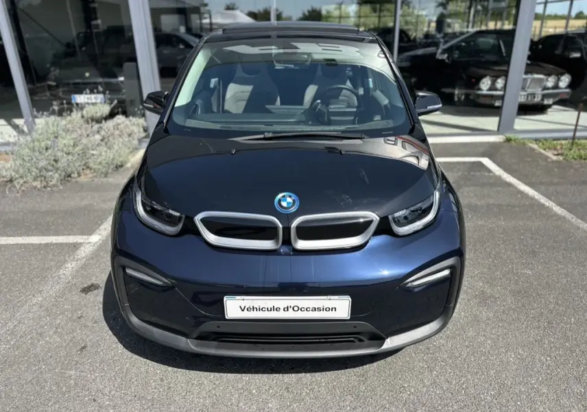 Vue avant d'une BMW i3 électrique bleu foncé avec capot noir et plaque "Véhicule d'Occasion" visible.