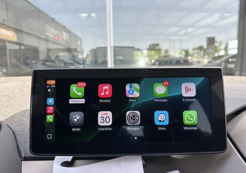 Écran tactile central de la BMW i3 2022 bleu, affichant les applications connectées en intérieur jour.