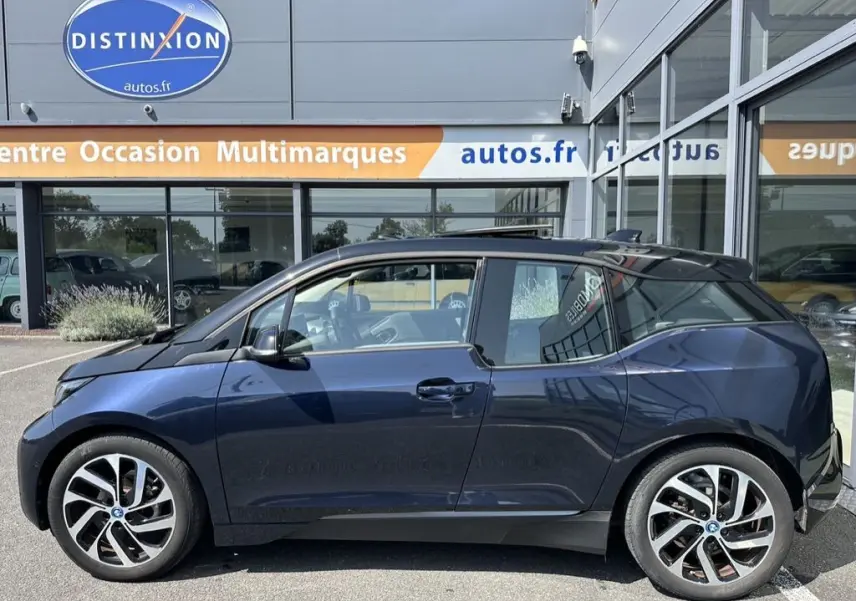 Profil côté gauche d'une BMW I3 électrique bleue édition Windmill Atelier 2022, avec jantes distinctives et toit noir.