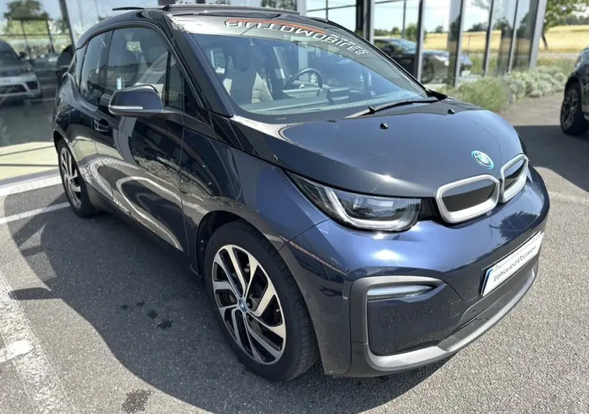 BMW i3 électrique bleue vue en 3/4 avant droit, avec capot noir et jantes distinctives bicolores.