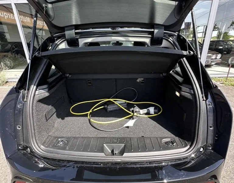 Vue arrière du coffre ouvert d'une BMW i3 bleue électrique 2022 avec câble de recharge visible à l'intérieur.