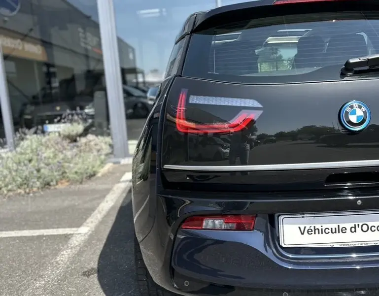 Vue arrière d'une BMW i3 électrique bleue 2022, mettant en valeur ses feux arrière LED distinctifs et son design compact.