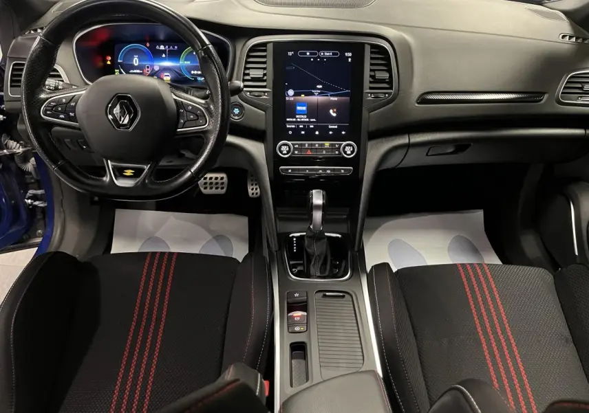 Intérieur Renault Mégane 1.6 E-Tech hybride, vue avant centrée sur tableau de bord, volant cuir R.S. Line et sièges noirs à surpiqûres rouges.