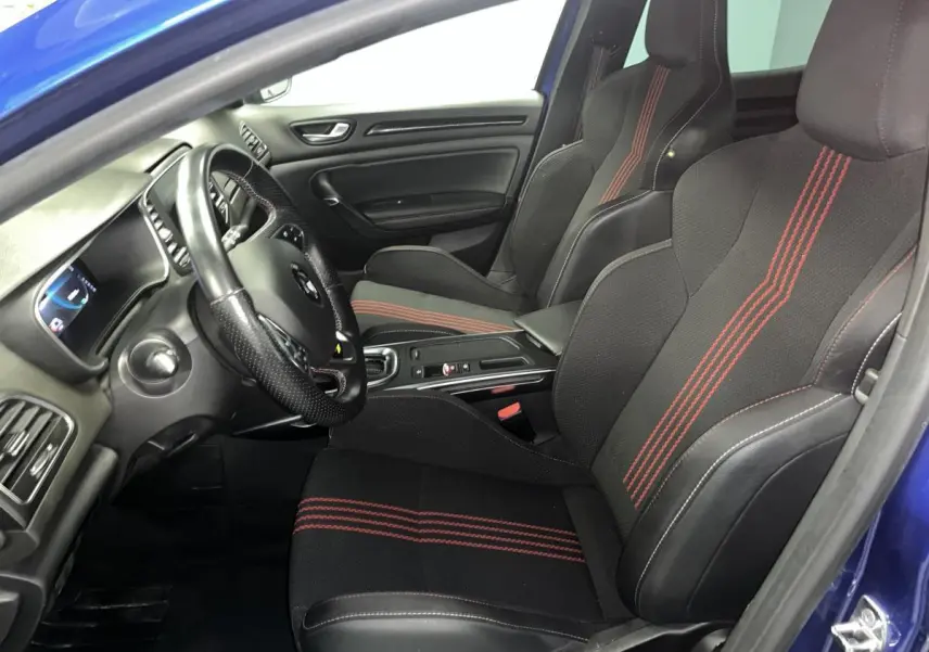 Vue intérieure côté conducteur de la Renault Mégane 1.6 E-Tech hybride bleue avec sièges sport noirs à surpiqûres rouges.