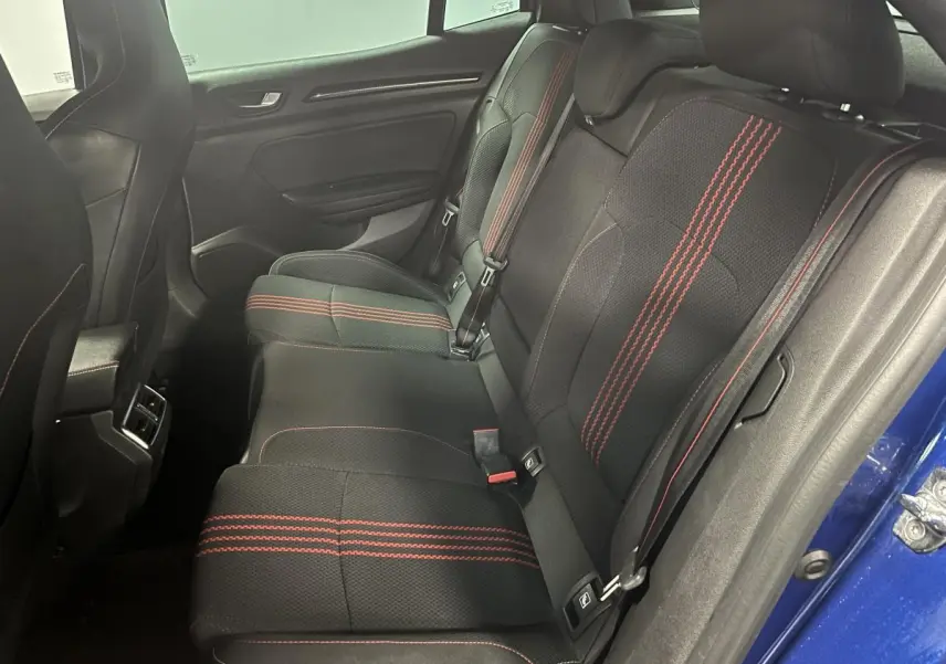 Vue latérale droite de l'intérieur arrière de la Renault Mégane bleu, sièges noirs avec surpiqûres rouges sportives.