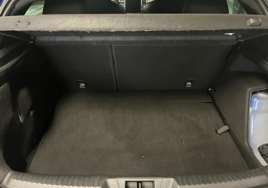 Coffre ouvert de la Renault Mégane hybride rechargeable bleue, montrant un espace de rangement noir et la trappe arrière.