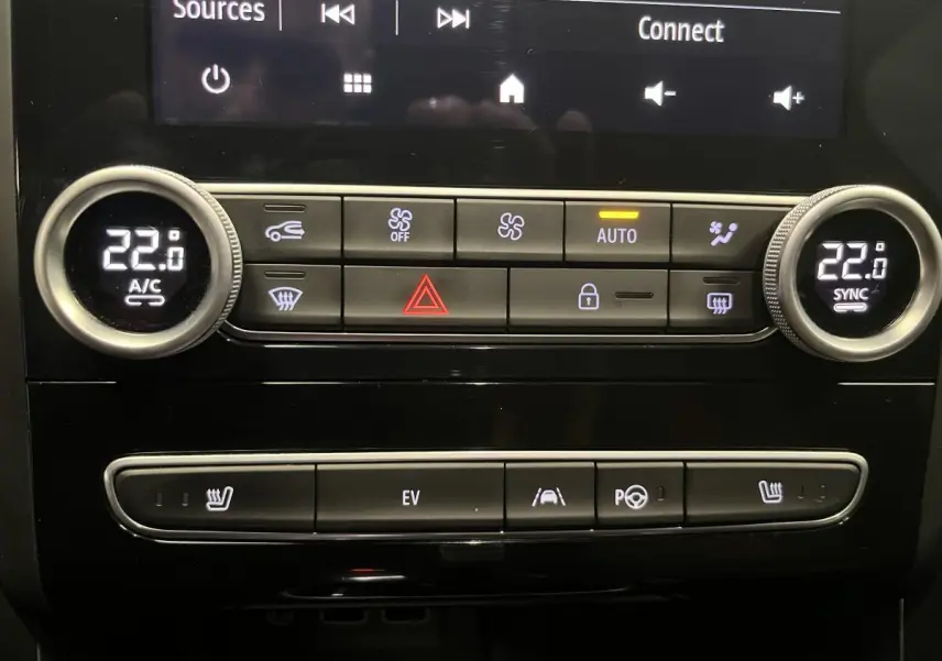 Gros plan sur la console centrale de la Renault Mégane hybride bleue, affichant la climatisation bi-zone et commandes EV.