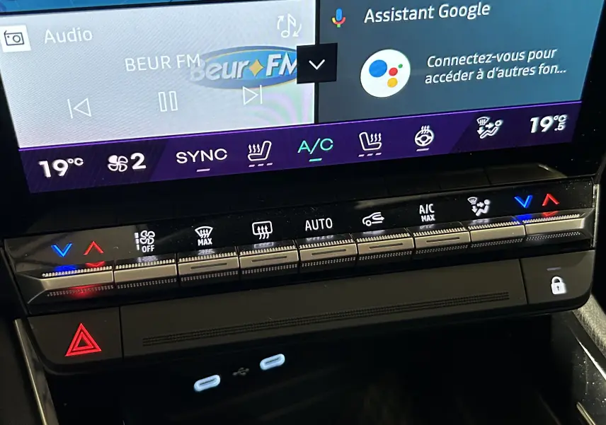Gros plan sur la console centrale du Renault Austral blanc nacré satin, affichant l’écran tactile et les commandes climatisation.