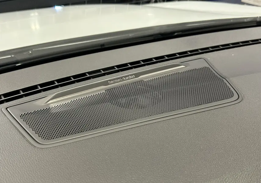 Gros plan sur la grille du haut-parleur Harman Kardon intégrée au tableau de bord du Renault Austral blanc nacré.