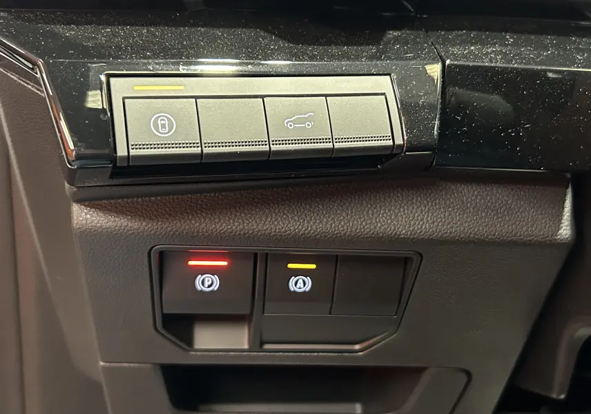 Gros plan sur les commandes de la console intérieure du Renault Austral blanc nacré satin, avec boutons de parking et coffre.