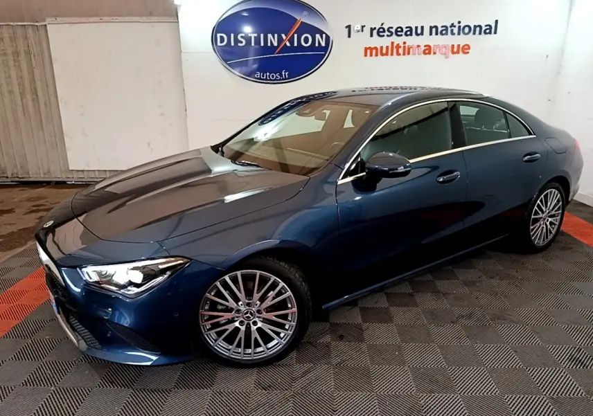 Vue 3/4 avant droite d'une Mercedes Classe CLA bleu métallisé avec jantes alliage multibranches dans un showroom.