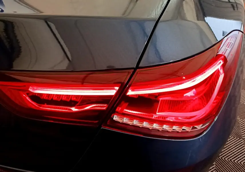 Gros plan sur le feu arrière droit rouge d'une Mercedes CLA 180 d Business Line blanche, détails lumineux nets.