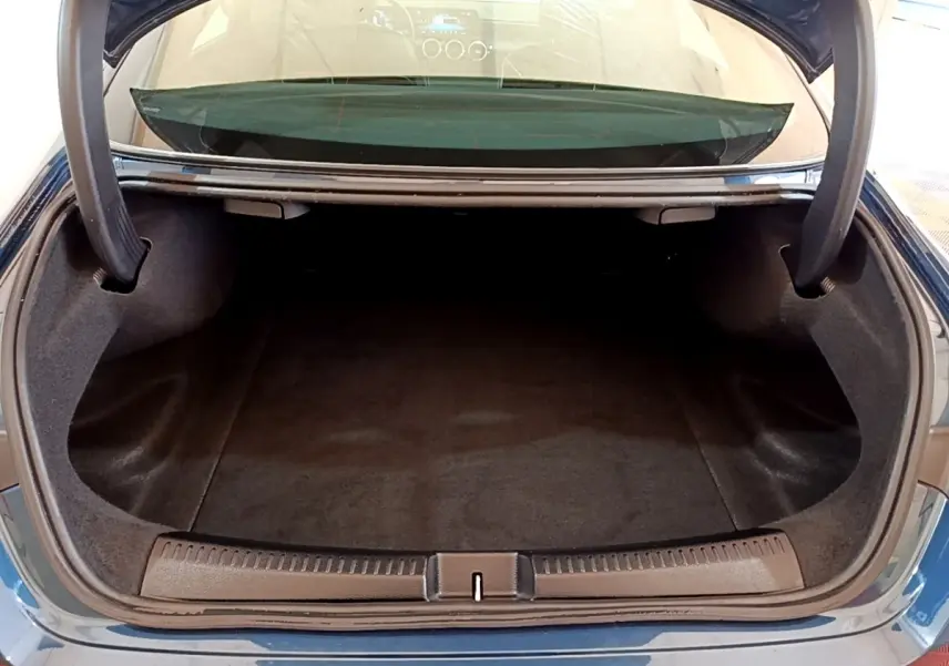 Coffre ouvert vu de l'arrière d'une Mercedes CLA 180 d Business Line blanche, intérieur noir et moquette propre.