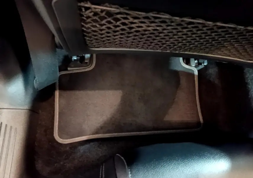 Vue intérieure du plancher côté passager arrière d'une Mercedes CLA 180 d Business Line blanche, tapis noir avec surpiqûres.