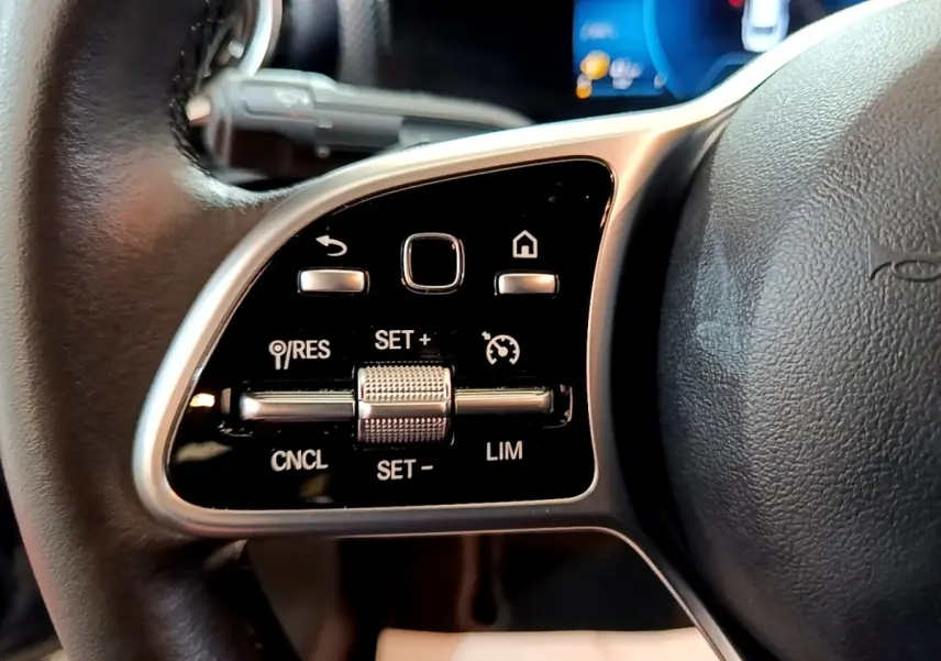 Gros plan sur les commandes multifonctions en alu et cuir du volant côté gauche d’une Mercedes CLA 180 d Business Line 2021.