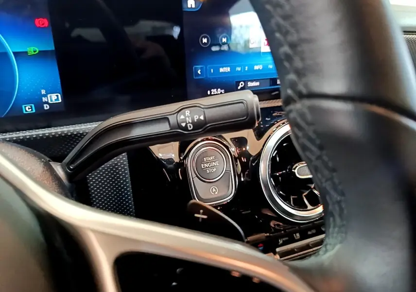 Gros plan intérieur sur le volant cuir et alu d’une Mercedes CLA 180 d blanche, avec bouton démarrage et écran digital.