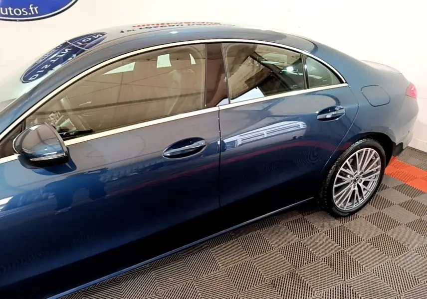 Vue latérale droite d'une Mercedes Classe CLA bleu métallisé avec jantes alliage multi-branches dans un showroom.