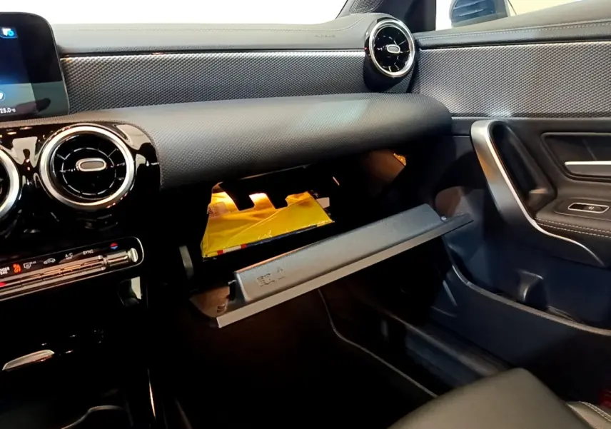 Vue intérieure côté passager de la Mercedes CLA 180 d Business Line 2021, tableau de bord noir et boîte à gants ouverte.