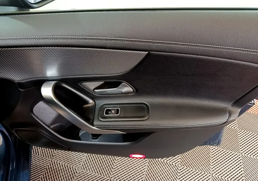 Vue rapprochée de la porte côté gauche noire de la Mercedes CLA 180 d Business Line avec poignée alu et bouton de vitre électrique.