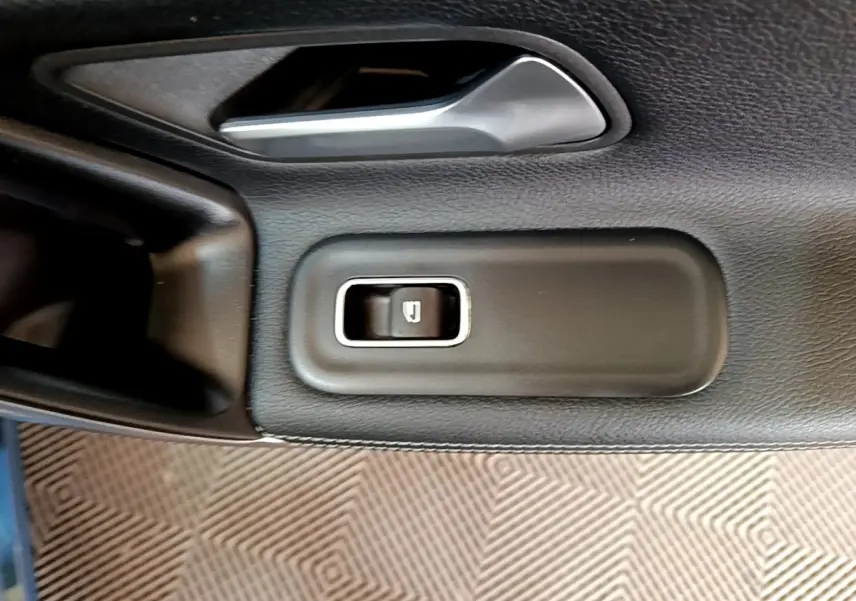 Gros plan sur le bouton de commande de la vitre côté conducteur de la Mercedes CLA 180 d Business Line blanche.
