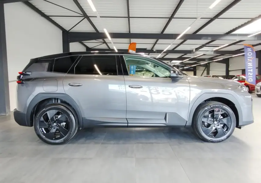 Vue latérale droite d'un Citroën C5 Aircross gris platine avec jantes alliage noires en intérieur showroom.