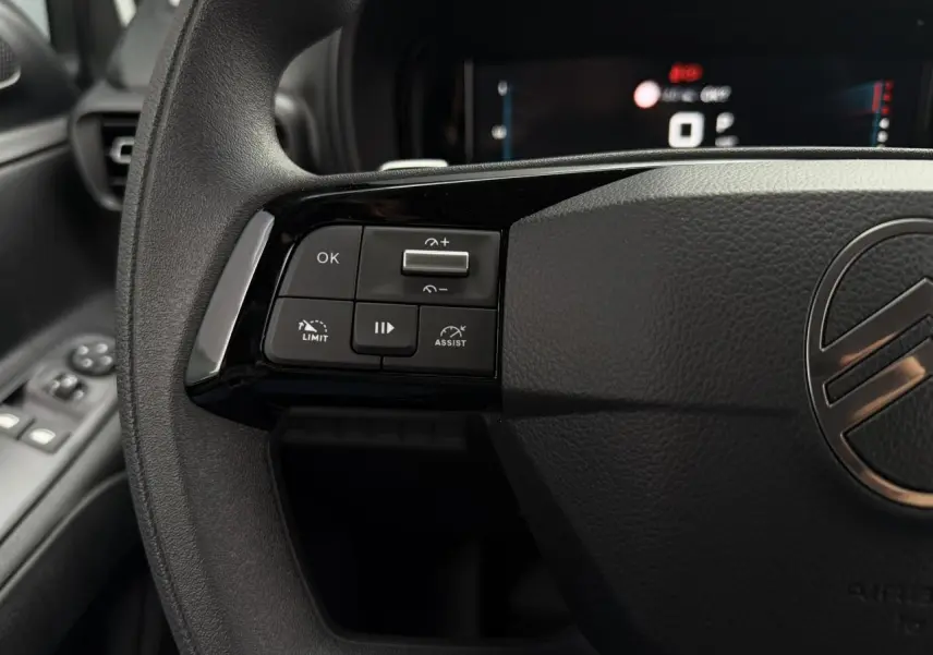 Gros plan sur le volant noir du Citroën Berlingo 2026 avec commandes multifonctions à gauche et logo central argenté.