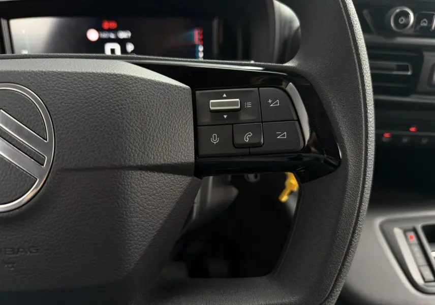 Gros plan sur les commandes multifonctions à droite du volant noir du Citroën Berlingo 2026, intérieur moderne.