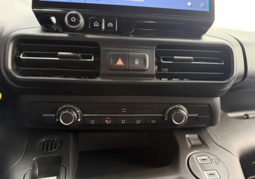 Vue rapprochée du tableau de bord noir du Citroën Berlingo 2026, montrant les aérateurs et commandes de climatisation.