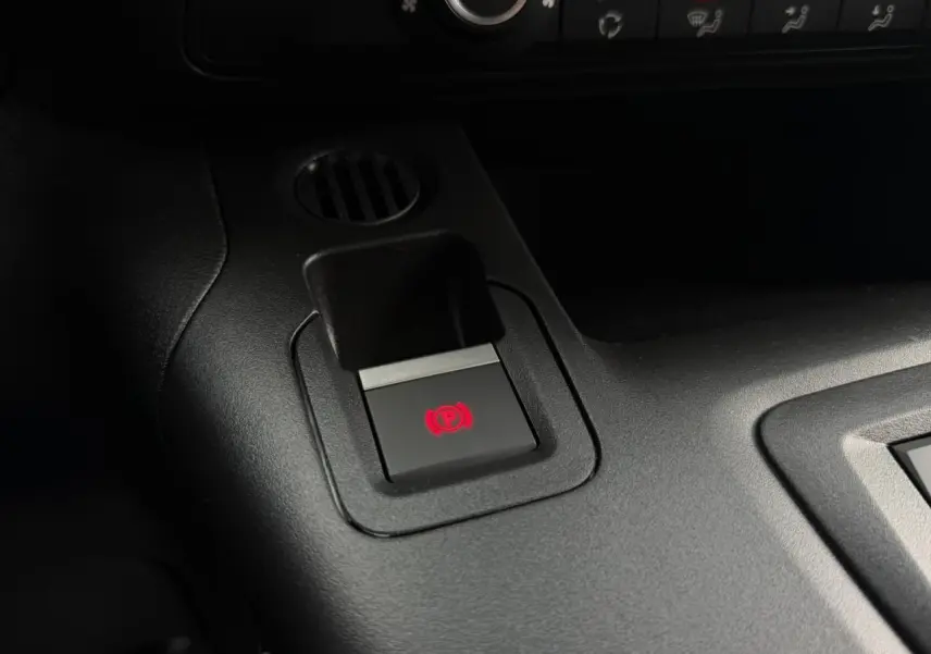 Gros plan sur le bouton de frein de stationnement électrique rouge dans l'habitacle noir du Citroën Berlingo Van XL 2026.