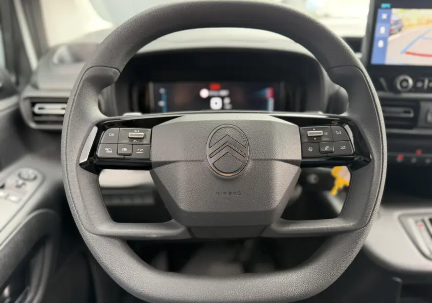 Vue rapprochée du volant multifonctions noir du Citroën Berlingo 2026 avec tableau de bord numérique et écran tactile visible.