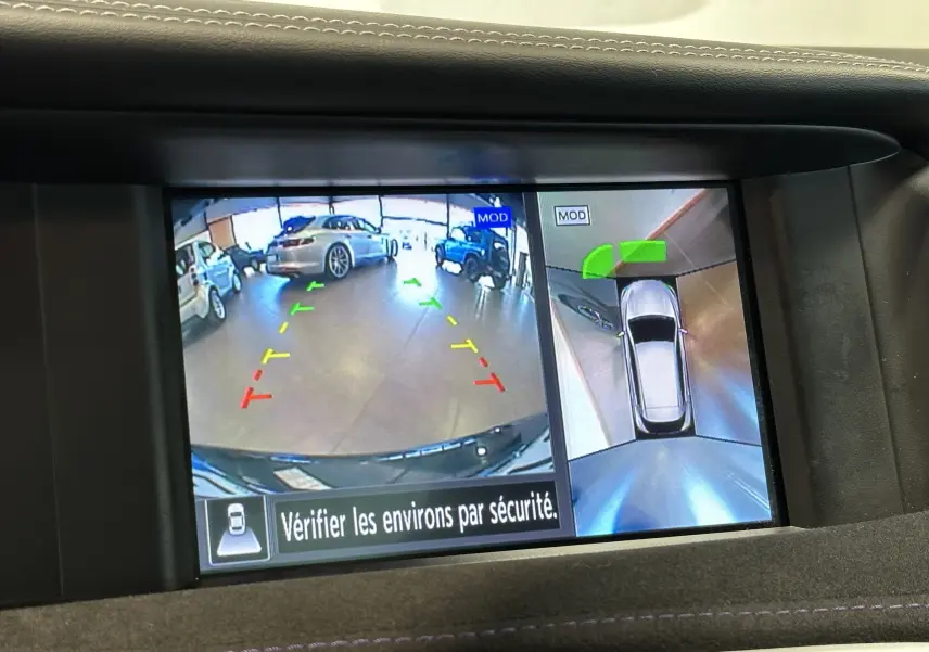 Vue écran caméra de recul et vue aérienne d'une Infiniti Q30 noire en stationnement intérieur avec repères colorés.