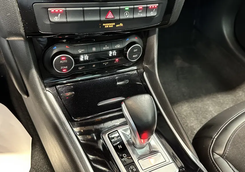 Gros plan sur la console centrale noire de l'INFINITI Q30 2016, avec levier de boîte auto et commandes climatisation allumées.