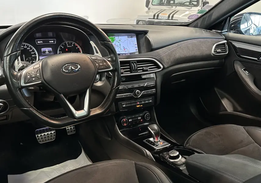Intérieur noir de l'INFINITI Q30 2.0t 2016, vue du poste de conduite avec volant multifonction et écran central tactile.