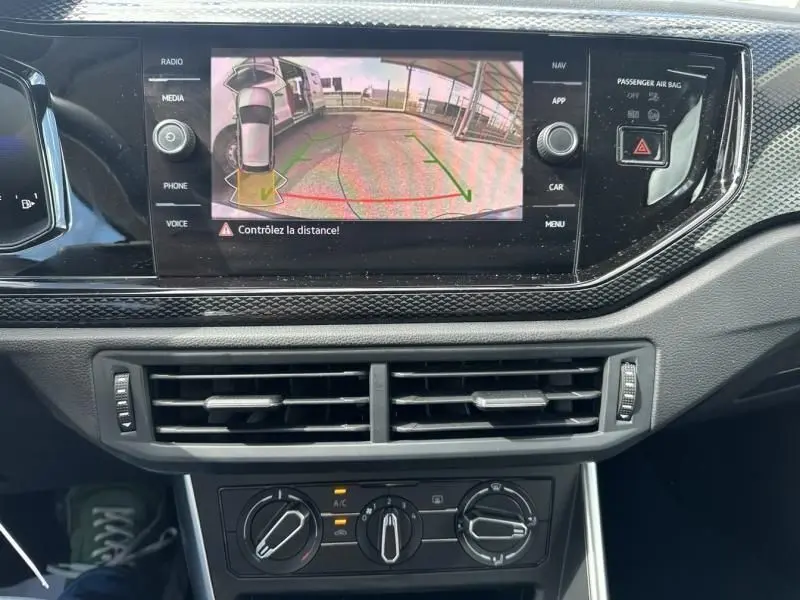 Vue de l'écran central du tableau de bord d'une Volkswagen Polo gris foncé 2024 affichant la caméra de recul avec guidage.