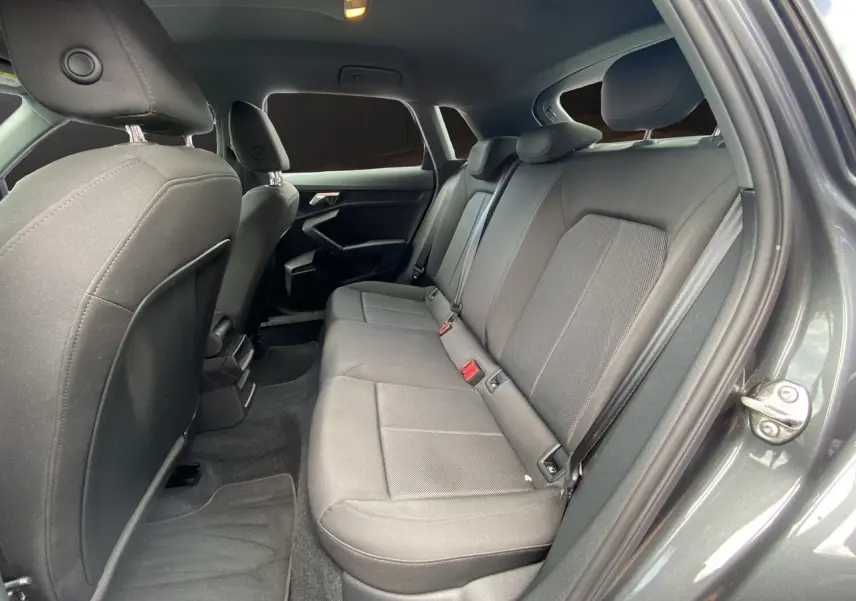 Vue intérieure arrière droite de l'Audi A3 Sportback 30 TFSI 110 S-Line 2021 avec sièges tissu noir et portières gris Daytona.