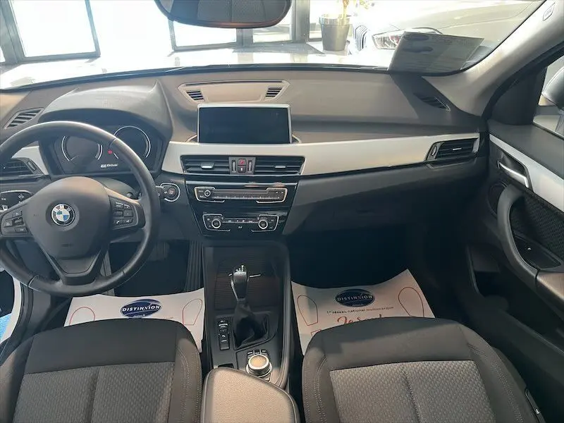 Vue intérieure avant du BMW X1 XDRIVE 25E avec tableau de bord moderne et volant multifonction noir.