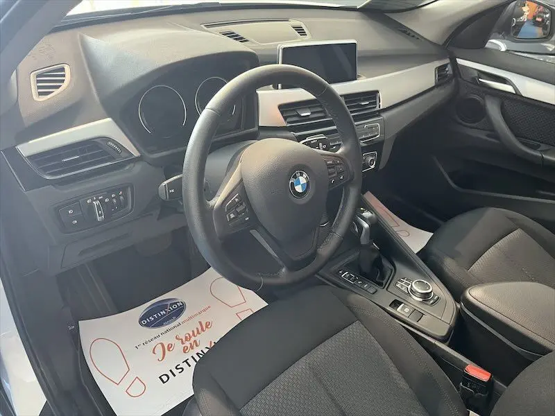 Intérieur noir de BMW X1 XDRIVE 25E 220CH 2021, vue côté conducteur sur volant et console centrale.