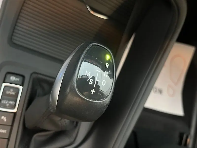 Le levier de vitesses automatique en gros plan à l'intérieur d'une BMW X1 blanche, avec indication mode parking active.