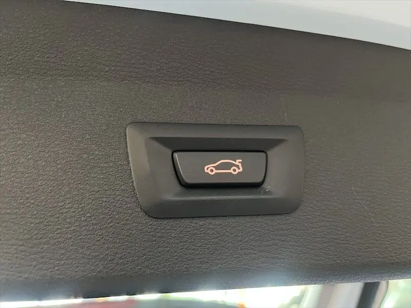 Bouton intérieur noir avec pictogramme orange d'ouverture du coffre, présent sur BMW X1 XDRIVE blanc alpin 2021.