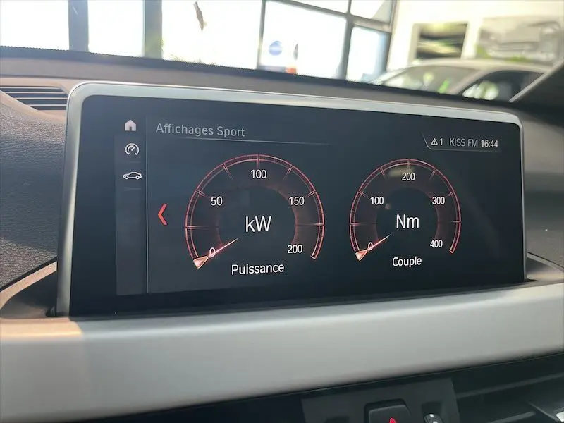 Écran central du tableau de bord de BMW X1 hybride rechargeable affichant la puissance et le couple en mode sport.