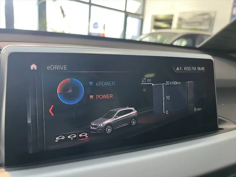 Écran multimédia montrant la consommation et l'énergie du BMW X1 XDRIVE blanc alpin en vue latérale droite.