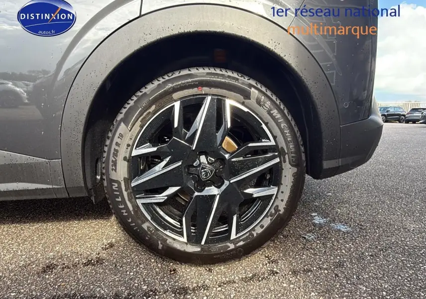 Gros plan sur la roue arrière droite du Peugeot 3008 gris titane avec jante alu noire et argentée design étoilé.