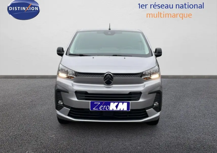 Vue frontale d'un Citroën Jumpy gris Artense Metal avec calandre noire et feux allumés sur fond neutre.