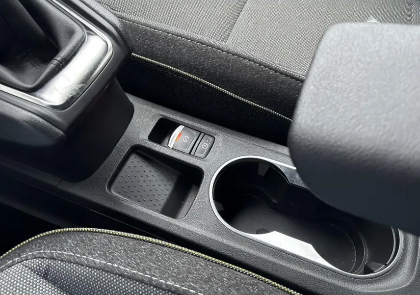 Gros plan sur la console centrale noire du Renault Captur 2025, avec frein à main électrique et accoudoir tissu.